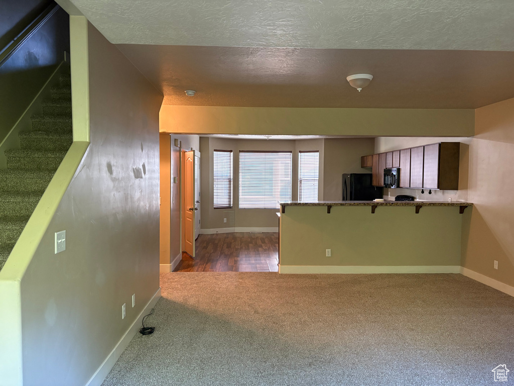 Interior space featuring carpet floors, a textured ceiling, baseboards, and stairs