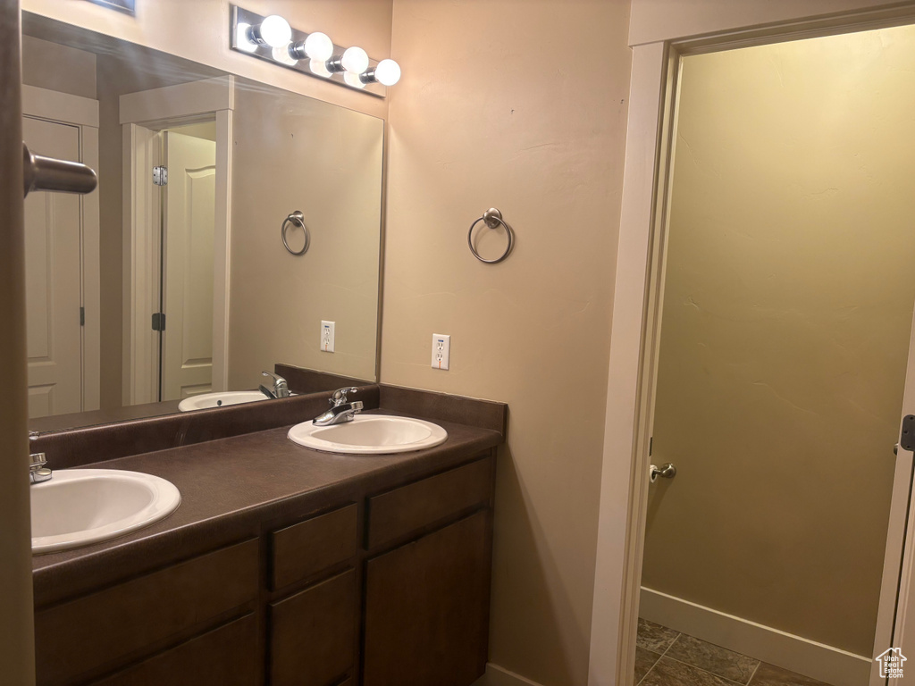 Full bathroom featuring double vanity, baseboards, and tile patterned flooring