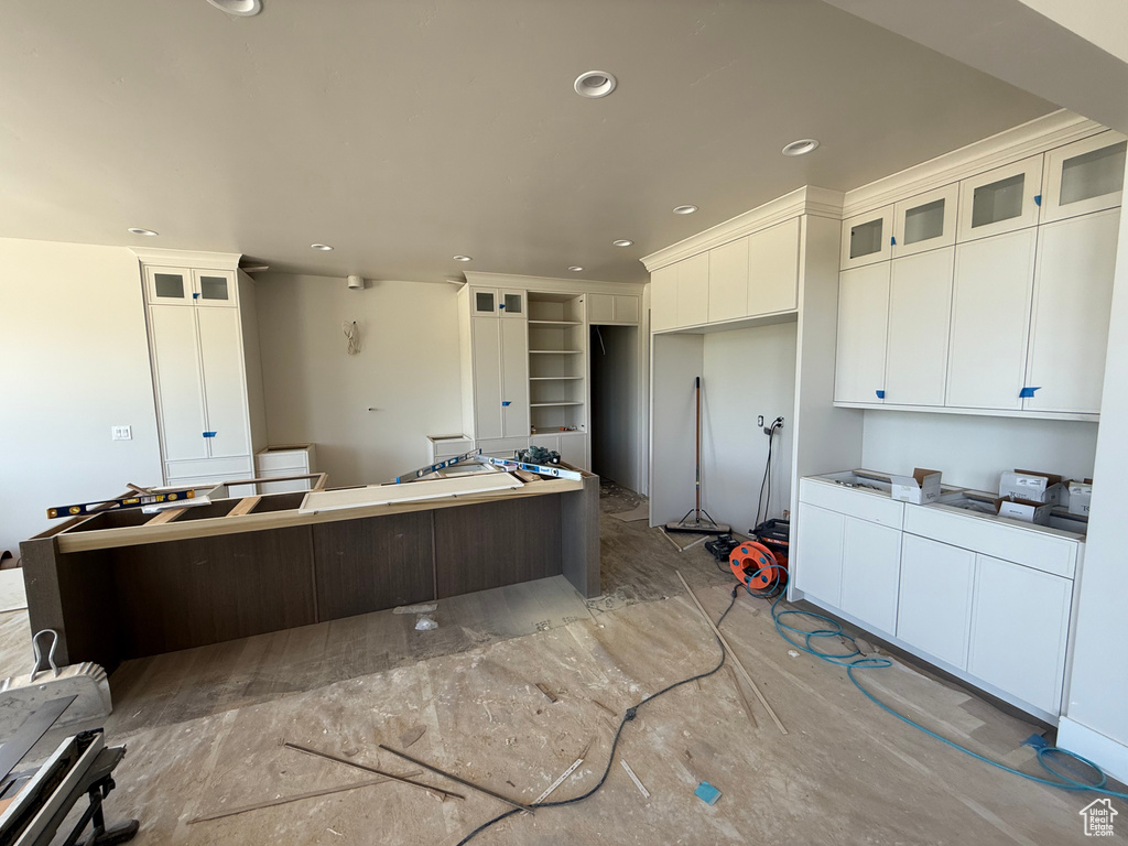 Kitchen with a center island, white cabinetry, recessed lighting, and glass insert cabinets