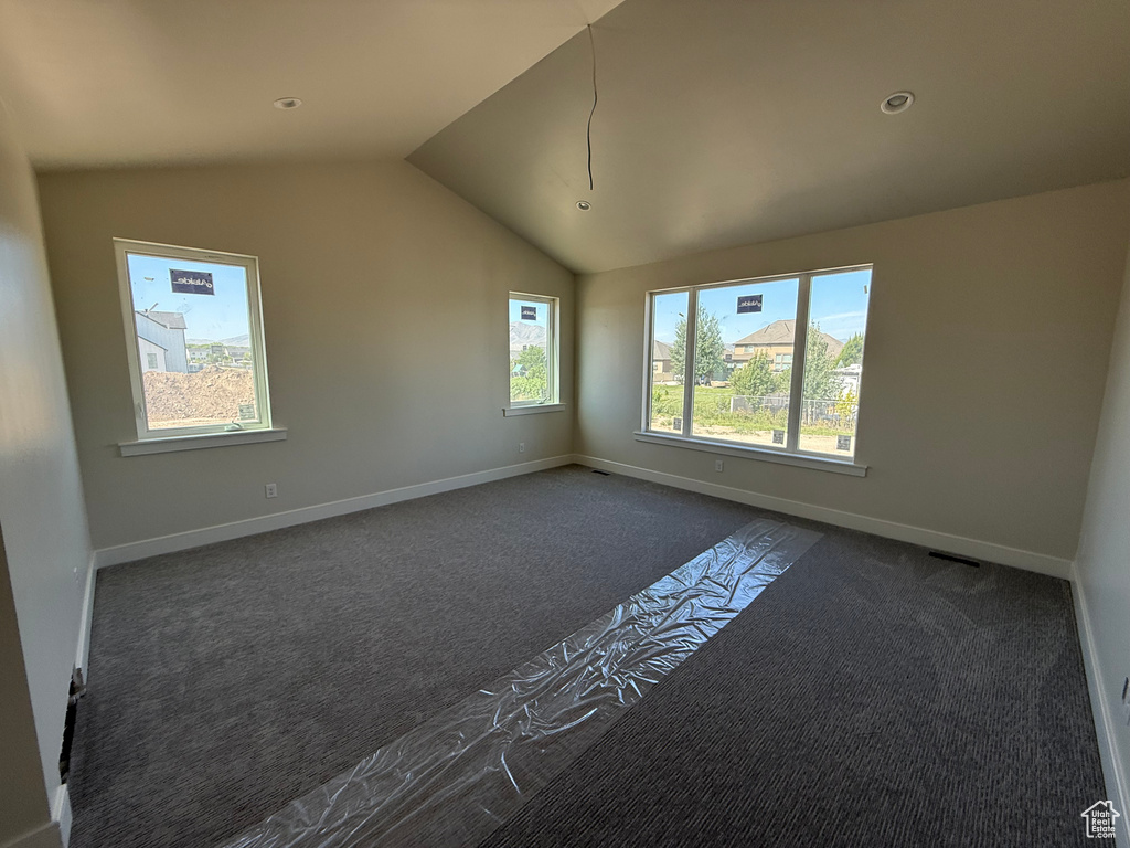 Empty room featuring dark carpet, vaulted ceiling, and recessed lighting