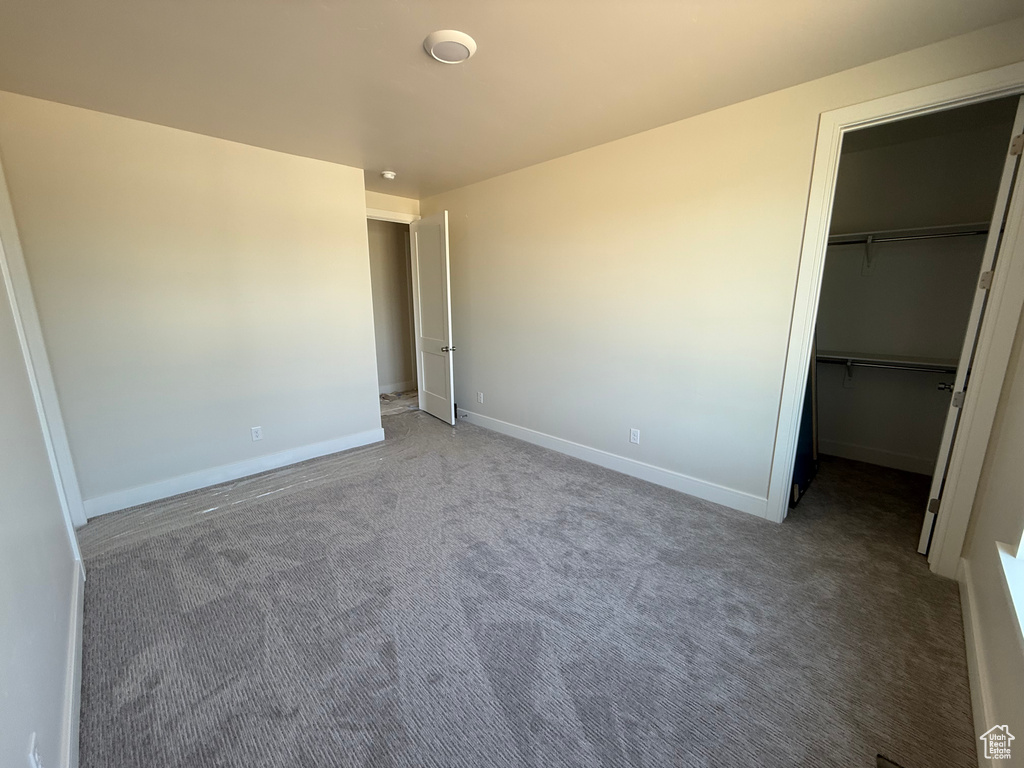 Unfurnished bedroom with carpet flooring, a walk in closet, and a closet