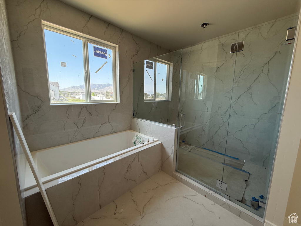 Bathroom featuring marble tiled floors, a garden tub, and a marble finish shower