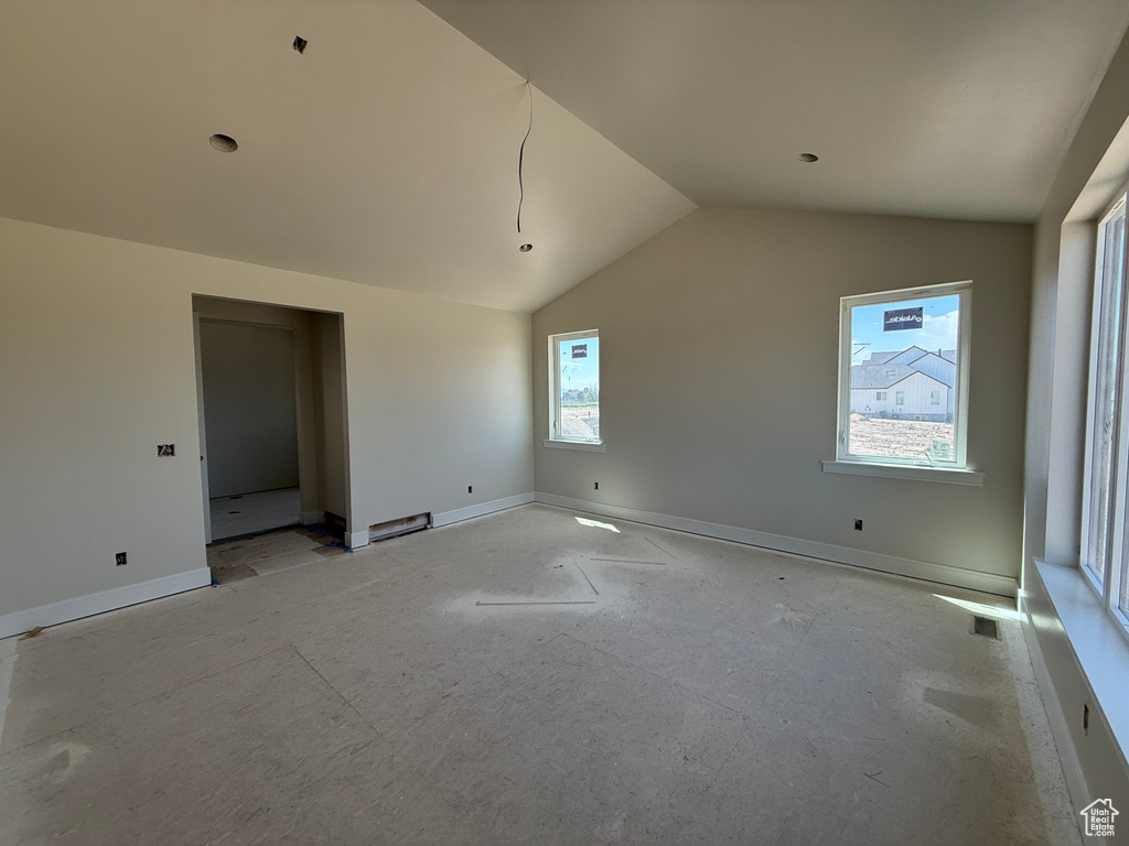 Spare room featuring lofted ceiling and baseboards