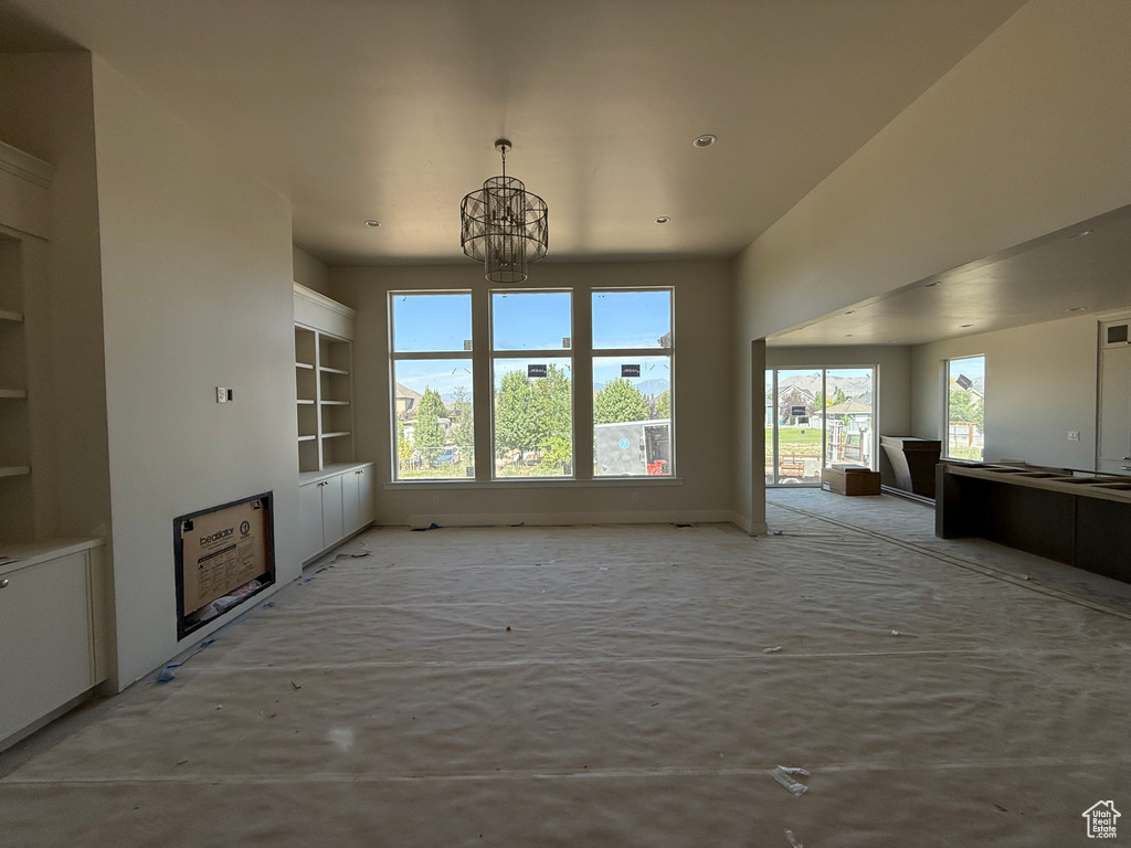 Unfurnished living room with a chandelier, built in shelves, and recessed lighting