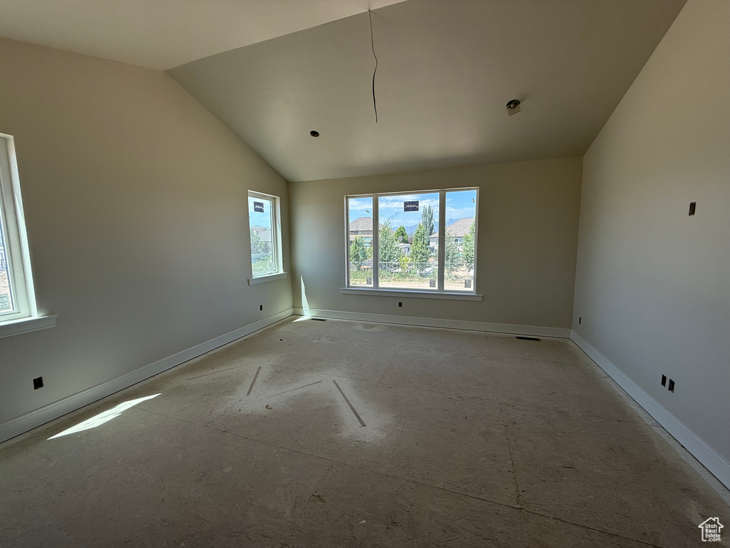 Unfurnished room featuring lofted ceiling and baseboards