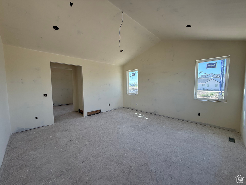 Unfurnished room featuring visible vents and vaulted ceiling