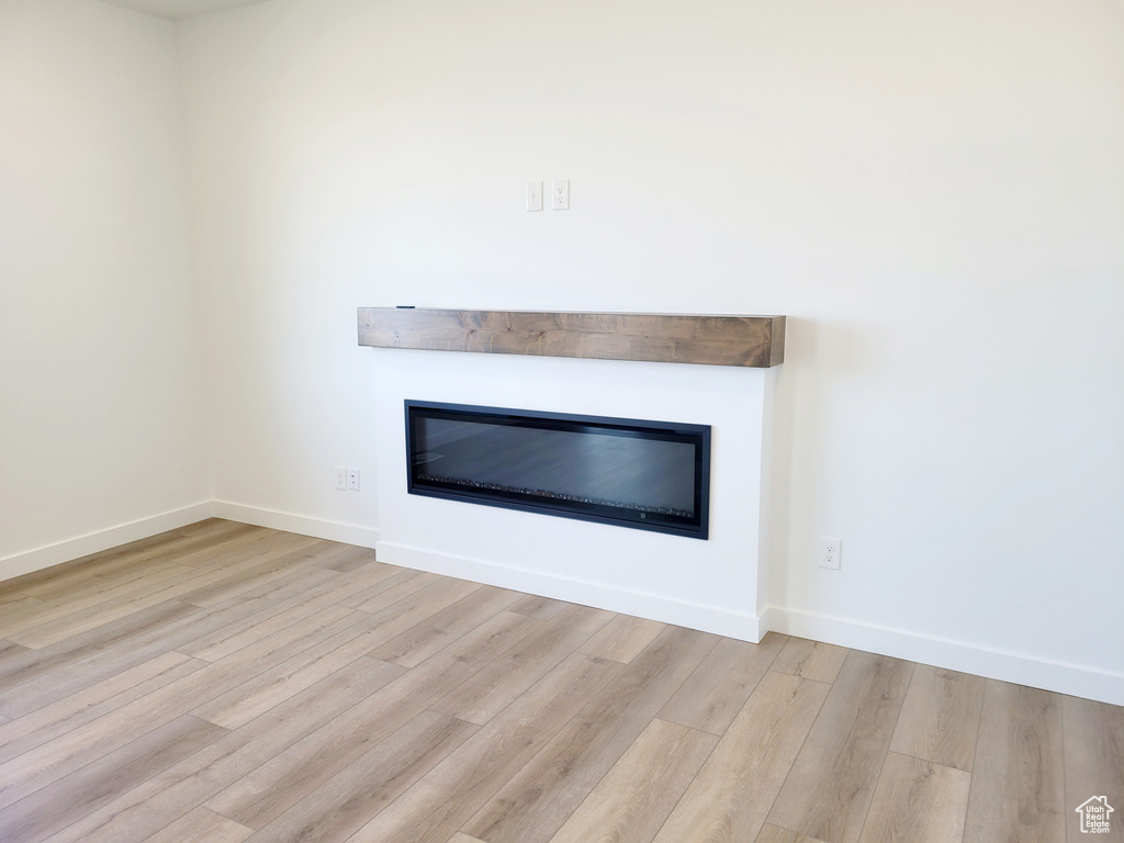 Room details featuring a glass covered fireplace, baseboards, and wood finished floors