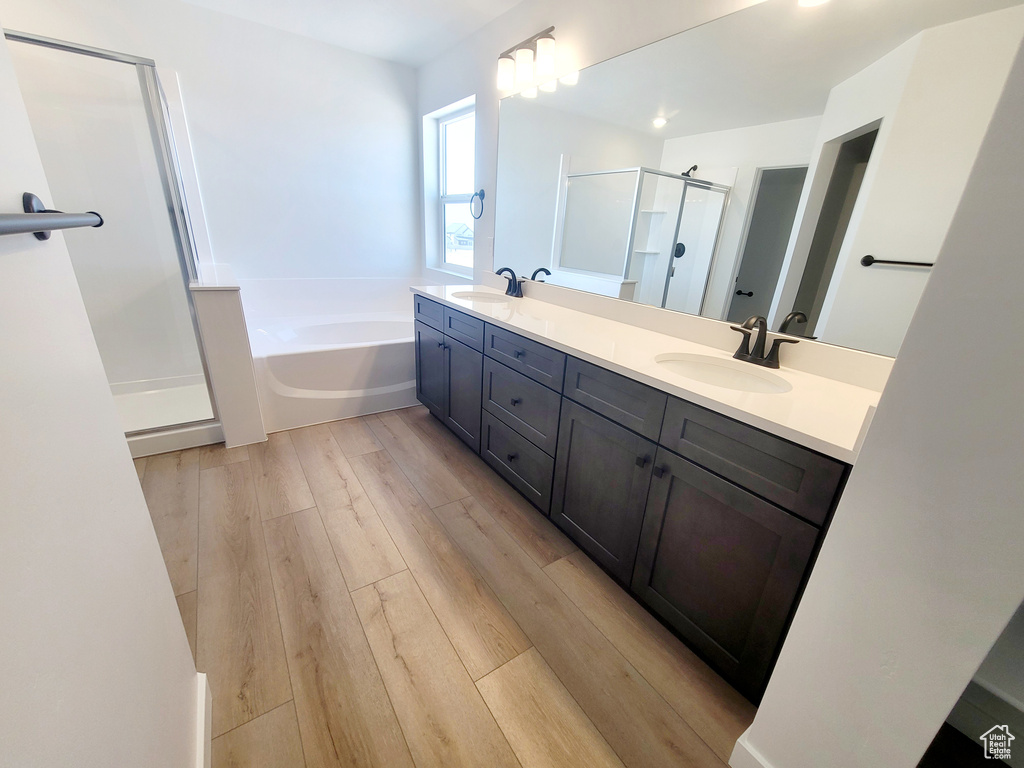 Bathroom featuring double vanity, a bath, a sink, and a stall shower