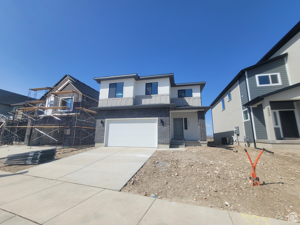 View of front of property with driveway, a garage, and brick siding