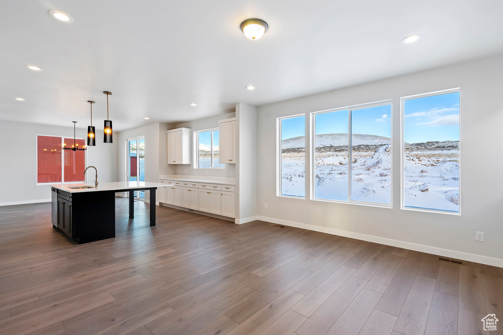 Unfurnished living room with baseboards, a notable chandelier, a sink, dark wood-style floors, and recessed lighting