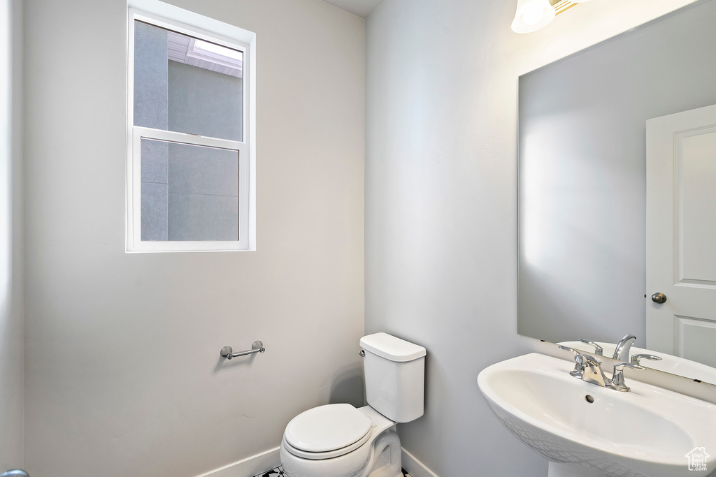 Half bath with toilet, a sink, and baseboards