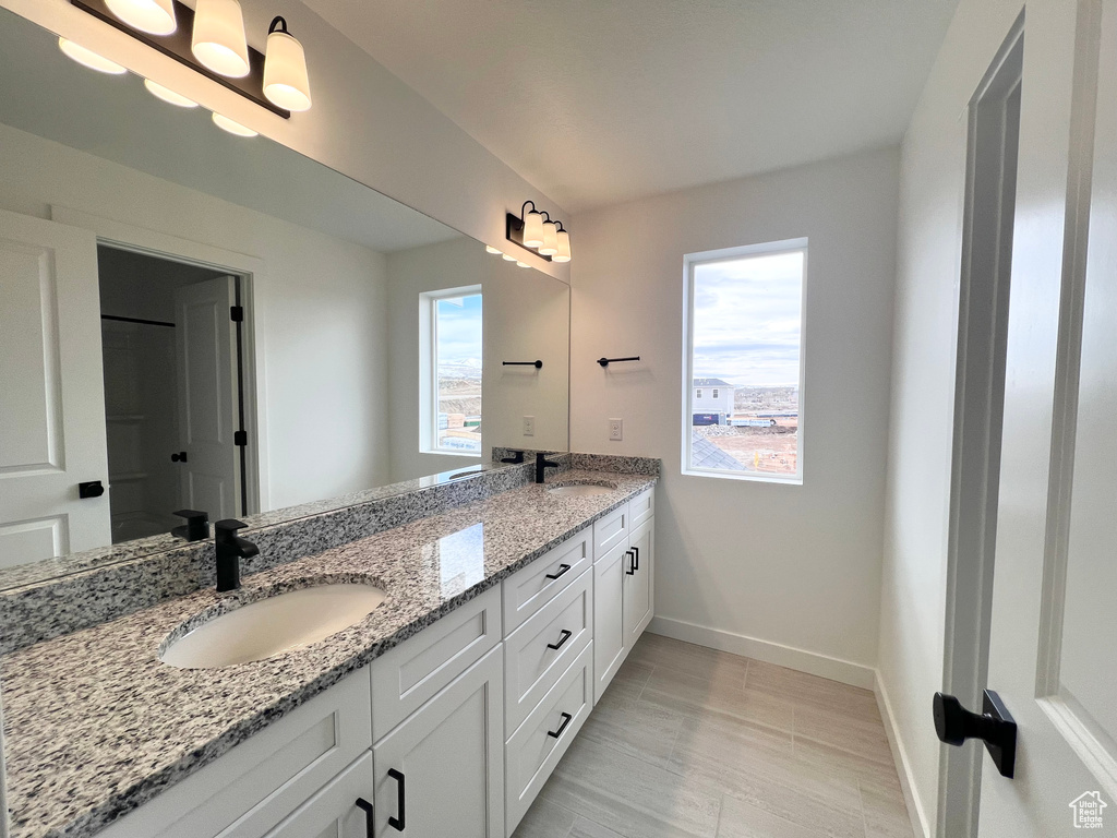 Full bath featuring double vanity, a sink, and baseboards