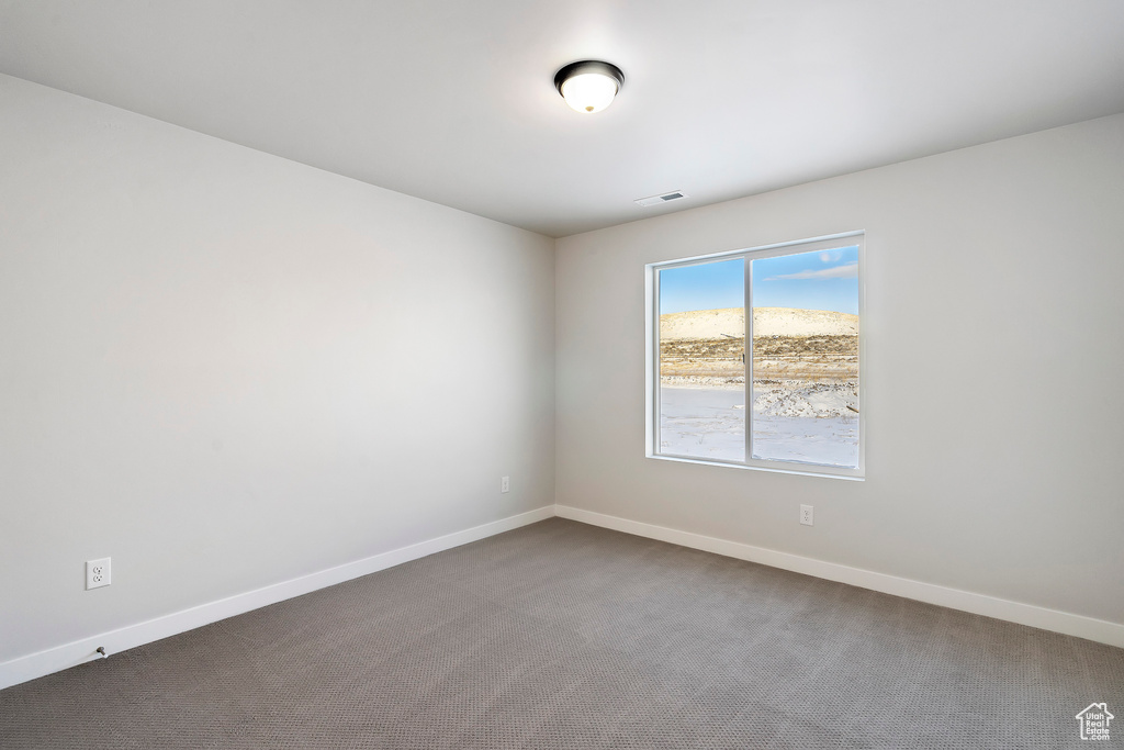 Empty room with visible vents, baseboards, and dark carpet