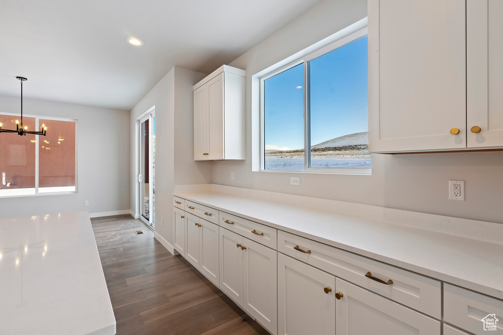 Kitchen with a chandelier, recessed lighting, light countertops, white cabinetry, and dark wood finished floors