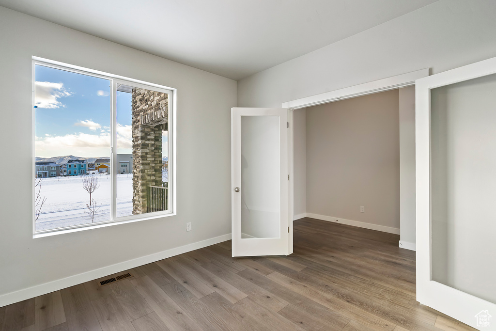 Unfurnished bedroom featuring wood finished floors, multiple windows, and visible vents