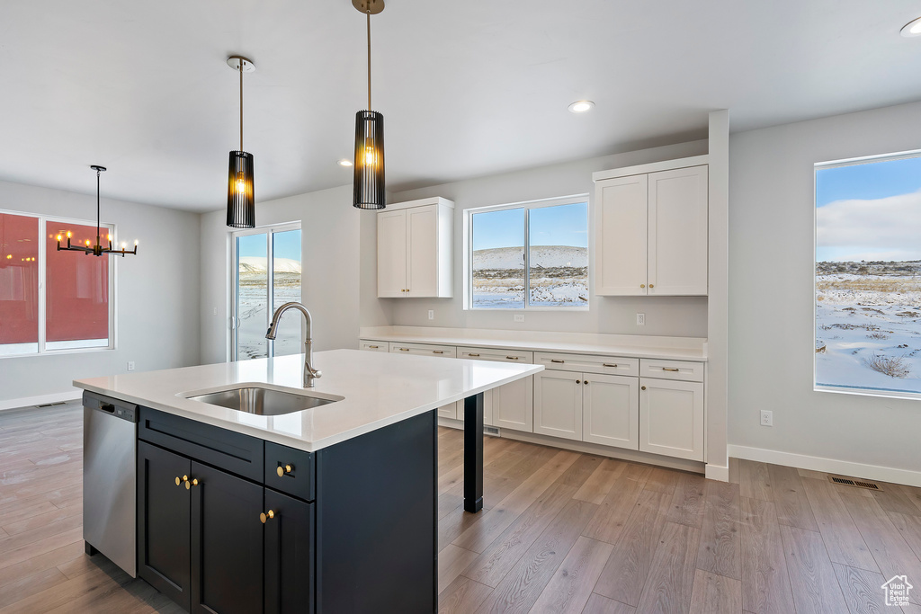 Kitchen with light countertops, dishwasher, a sink, and white cabinetry