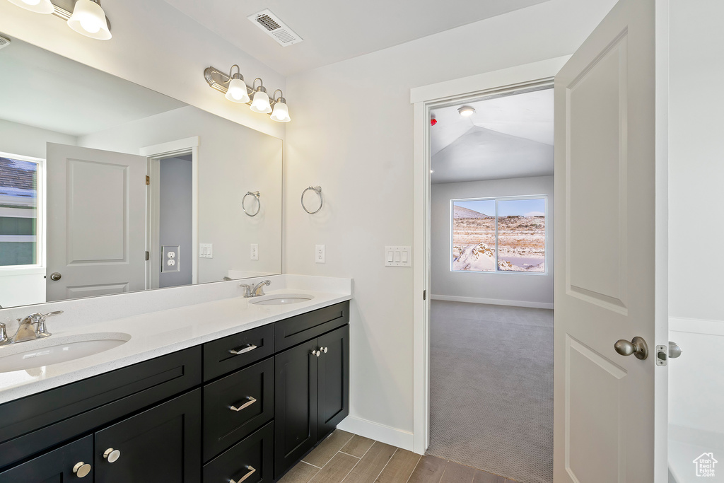 Bathroom with a sink, visible vents, baseboards, and double vanity