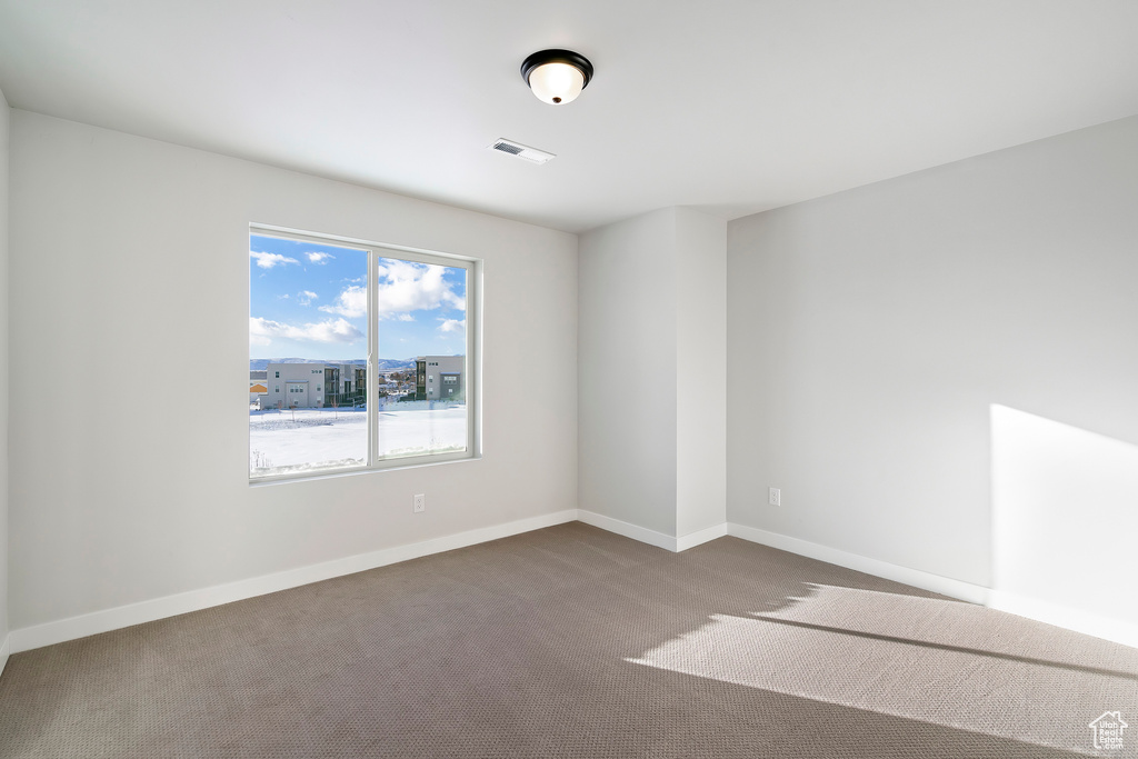 Unfurnished room featuring visible vents, baseboards, and carpet floors