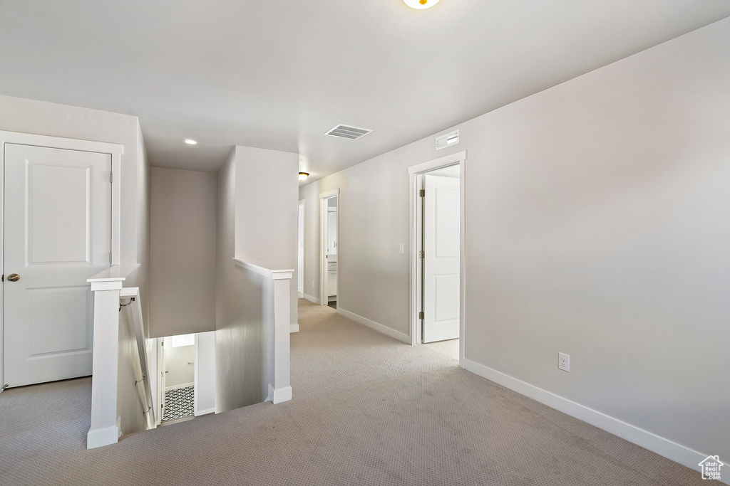 Spare room featuring light carpet, visible vents, and baseboards