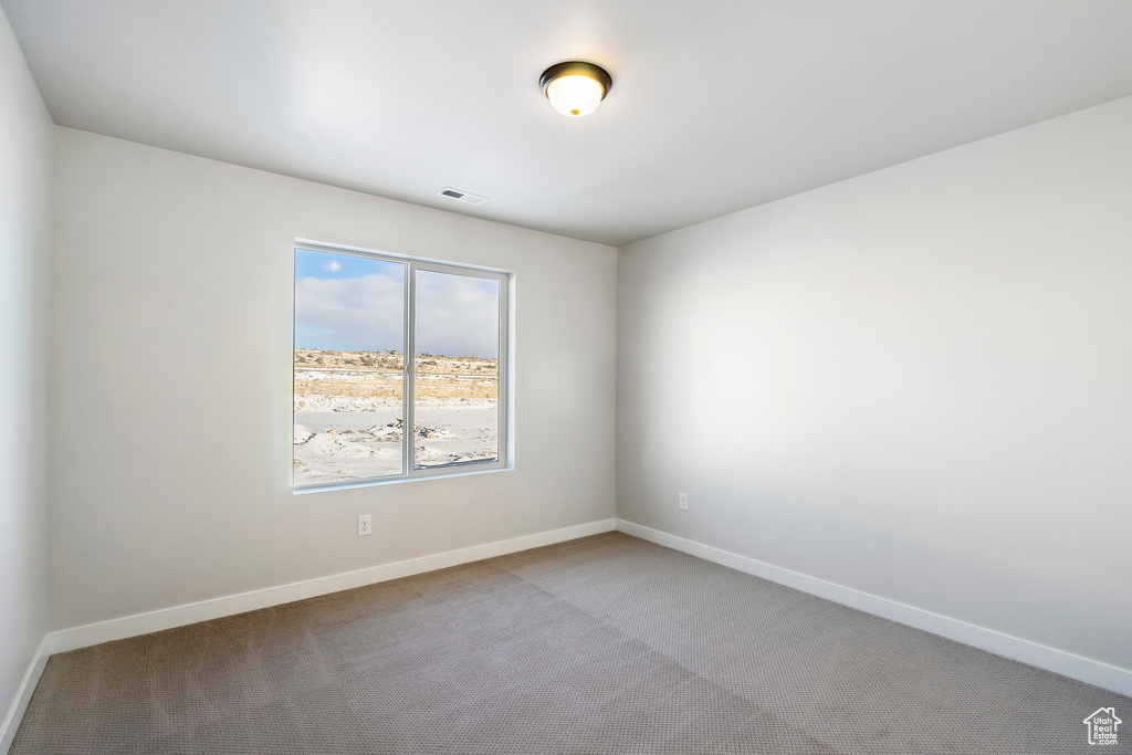 Empty room featuring carpet flooring, baseboards, and visible vents