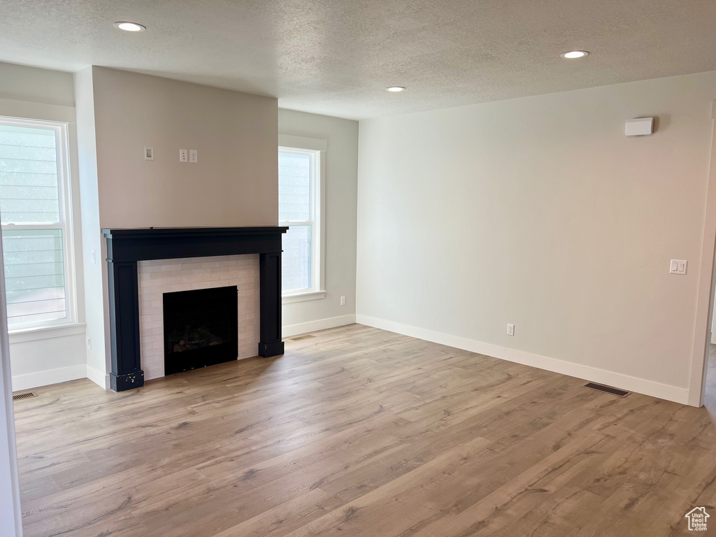 Unfurnished living room featuring a textured ceiling, wood finished floors, a fireplace, and recessed lighting
