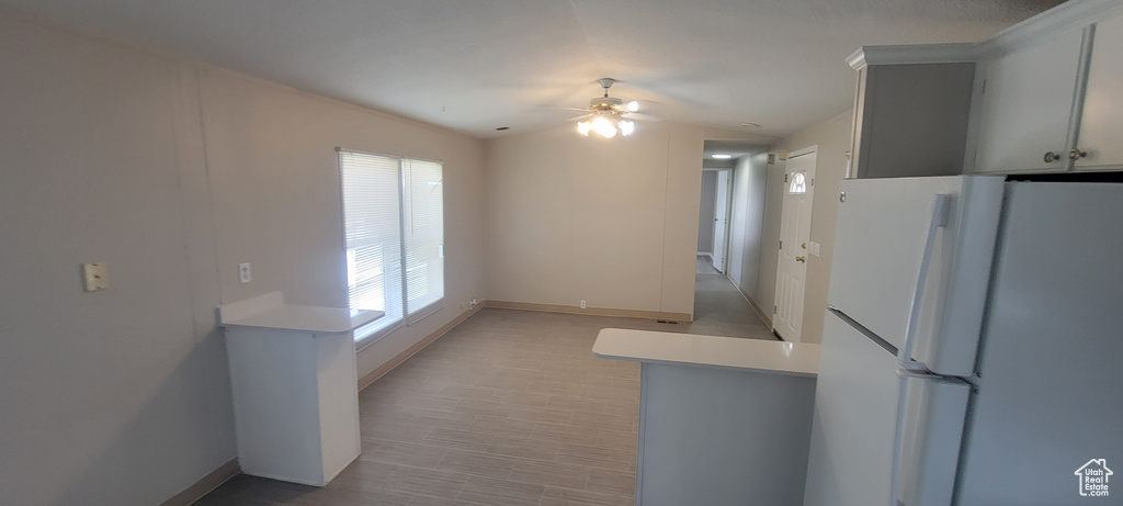 Kitchen with light countertops, baseboards, freestanding refrigerator, and a ceiling fan