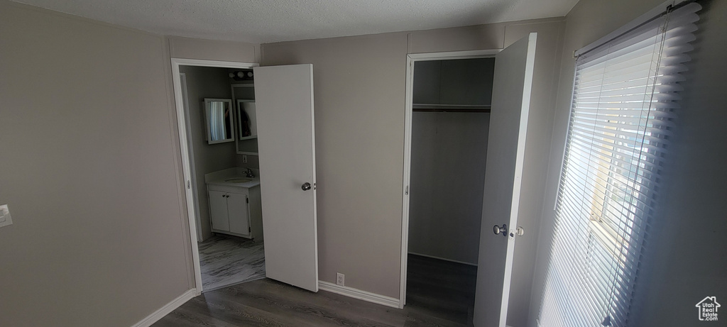 Unfurnished bedroom with baseboards, a closet, a sink, and wood finished floors
