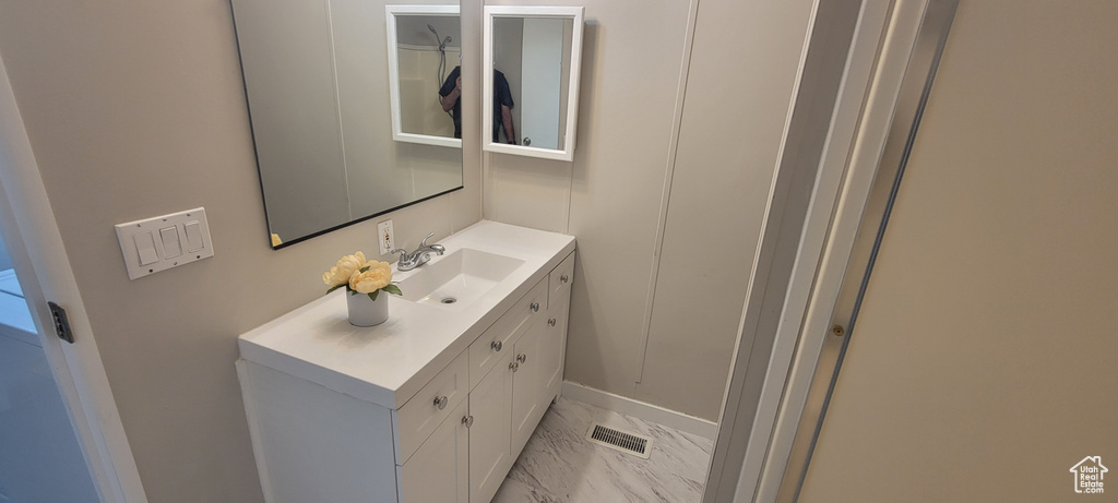 Bathroom with vanity, marble finish floor, and baseboards