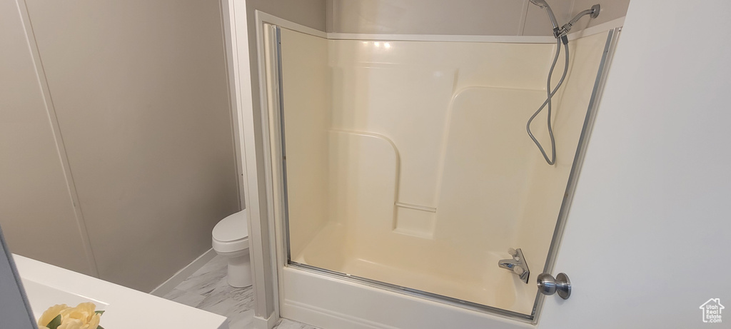 Bathroom featuring toilet, bathing tub / shower combination, and marble finish floor