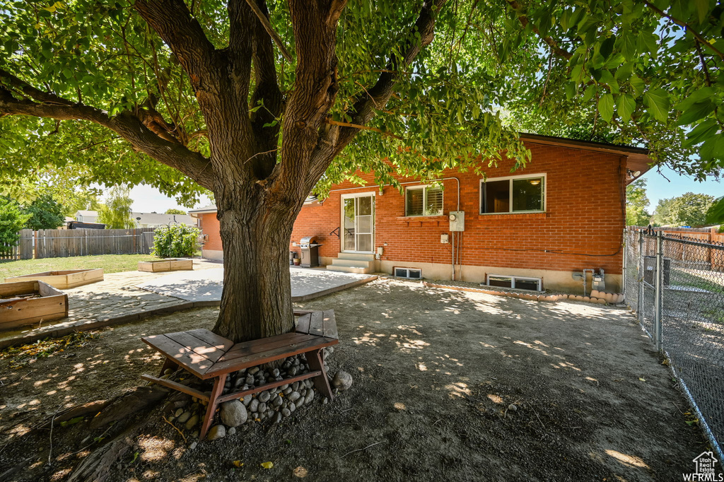 Rear view of property with entry steps, a patio, fence, and brick siding
