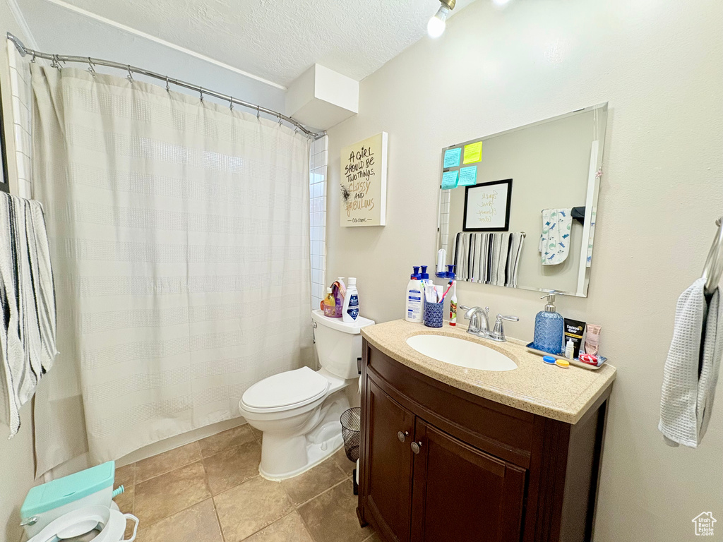Bathroom featuring toilet, curtained shower, vanity, and a textured ceiling