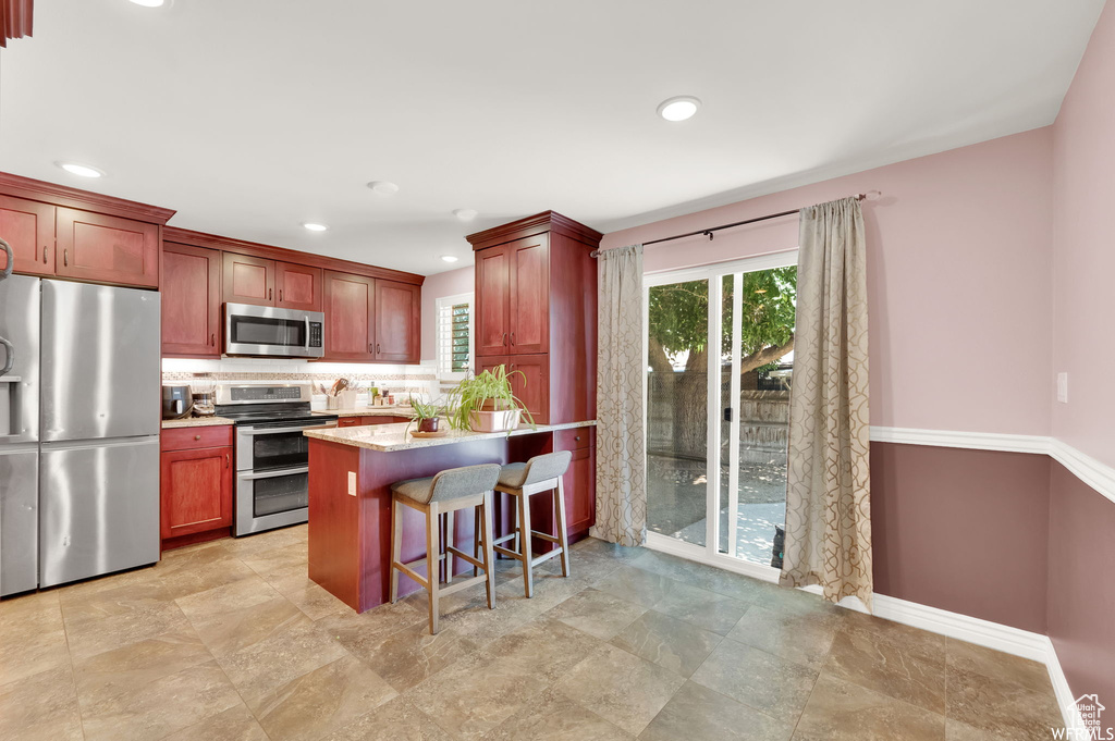 Kitchen with a peninsula, a wealth of natural light, appliances with stainless steel finishes, and decorative backsplash