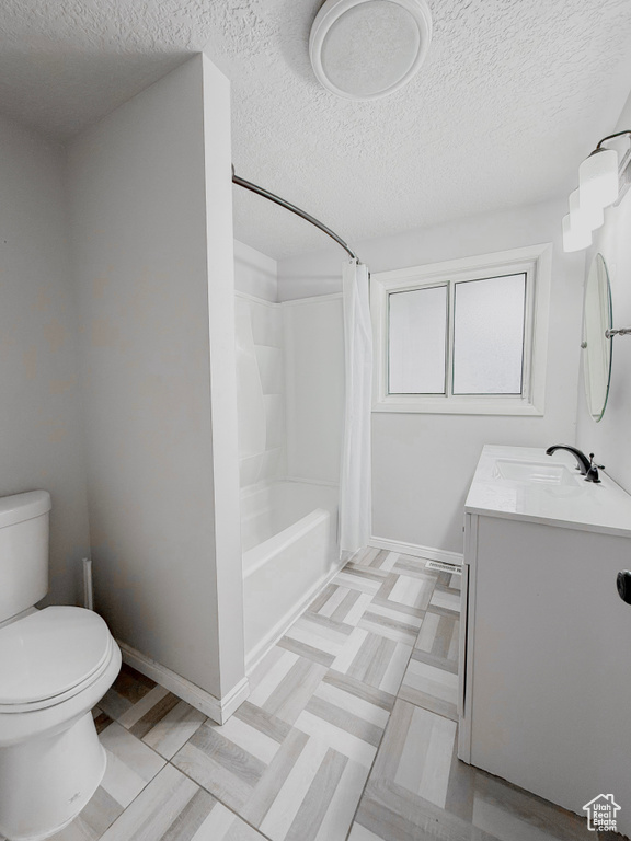 Bathroom with toilet, vanity, a textured ceiling, and baseboards