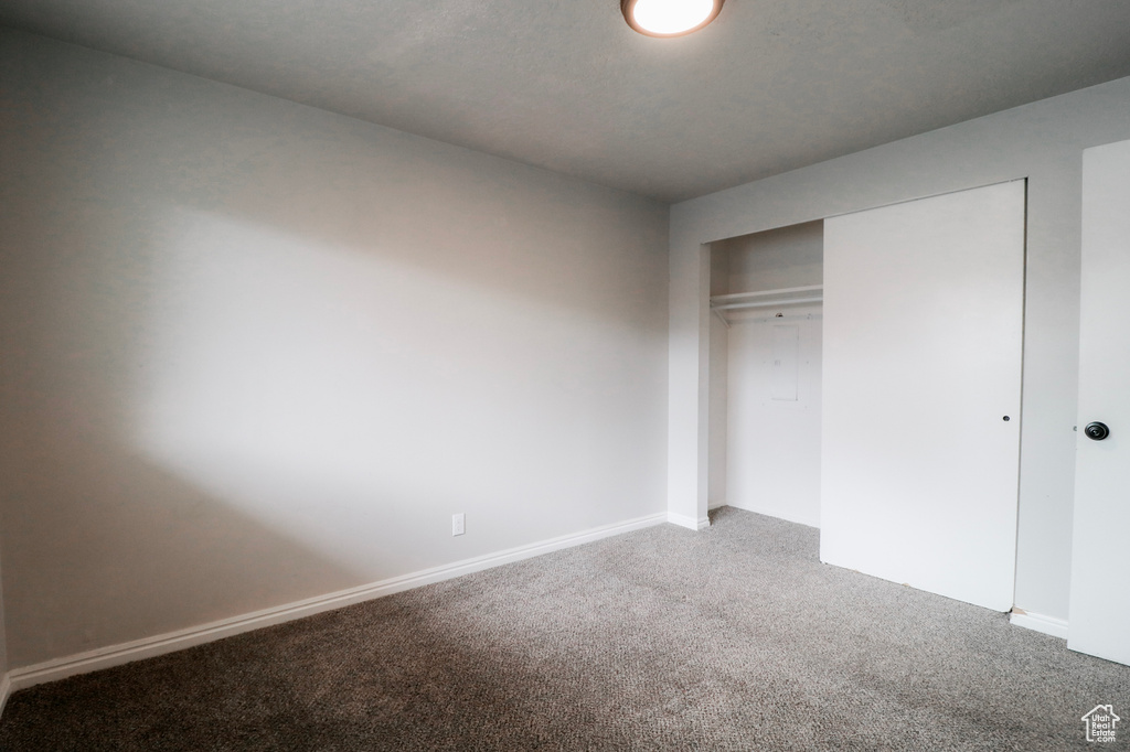 Unfurnished bedroom with baseboards, a closet, and light colored carpet