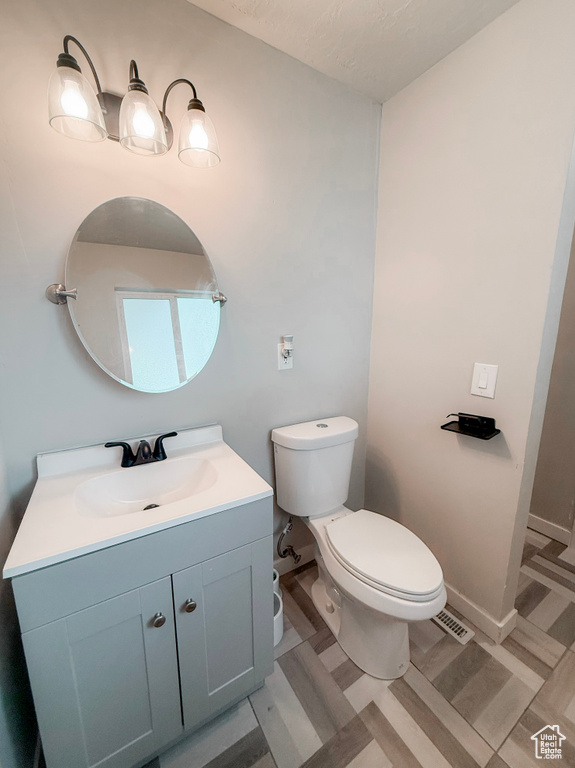 Bathroom featuring visible vents, toilet, and vanity