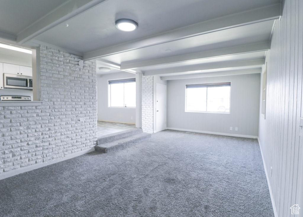 Spare room featuring baseboards, carpet flooring, and beam ceiling