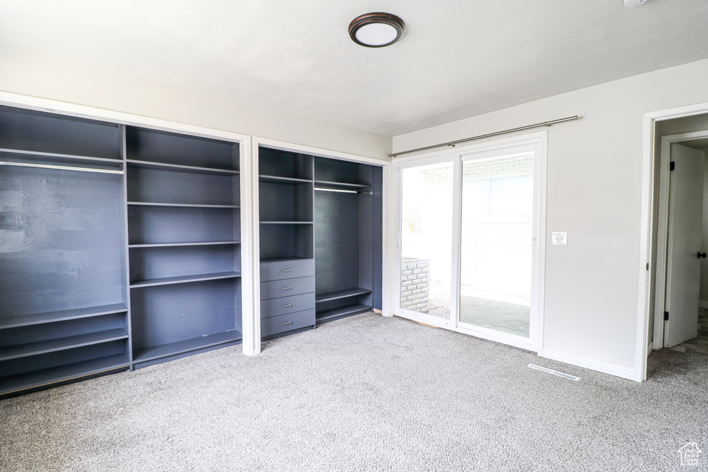 Unfurnished bedroom with carpet, multiple closets, and baseboards