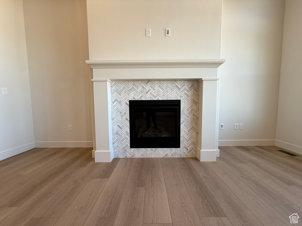 Detailed view of a tile fireplace, wood finished floors, and baseboards