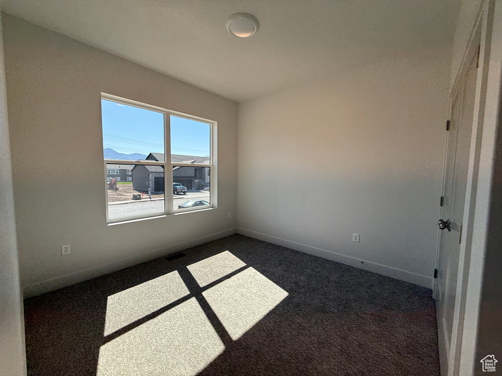 Unfurnished room with dark carpet and baseboards