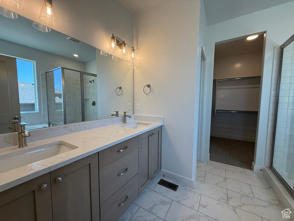 Full bathroom with a shower stall, marble look tiles, double vanity, baseboards, and a spacious closet