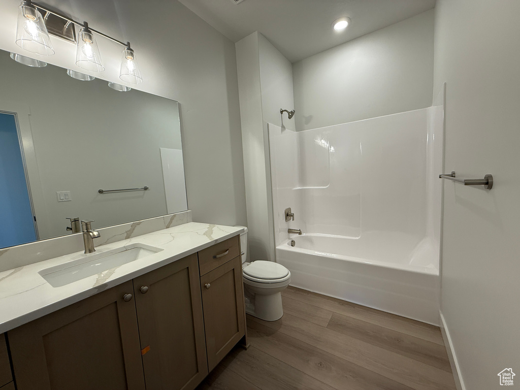 Bathroom featuring wood finished floors, toilet, vanity, and shower / tub combination