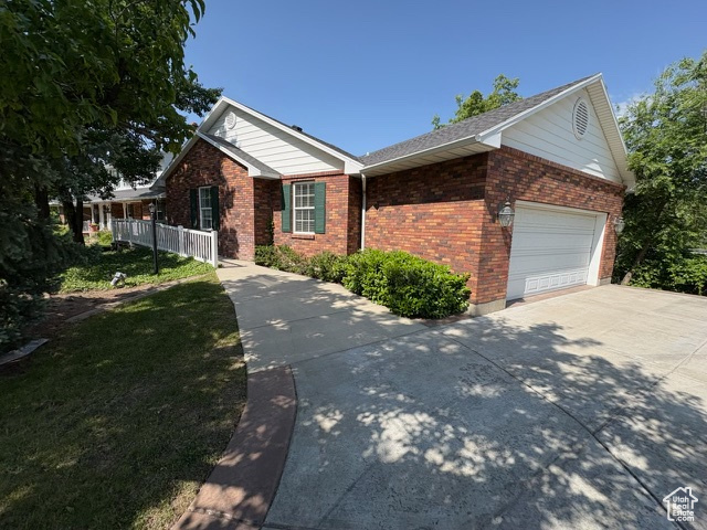 View of front of property featuring brick siding, driveway, and a garage