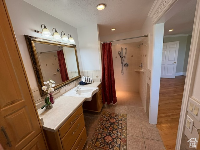 Bathroom with a shower with shower curtain, vanity, recessed lighting, tile patterned flooring, and a textured ceiling