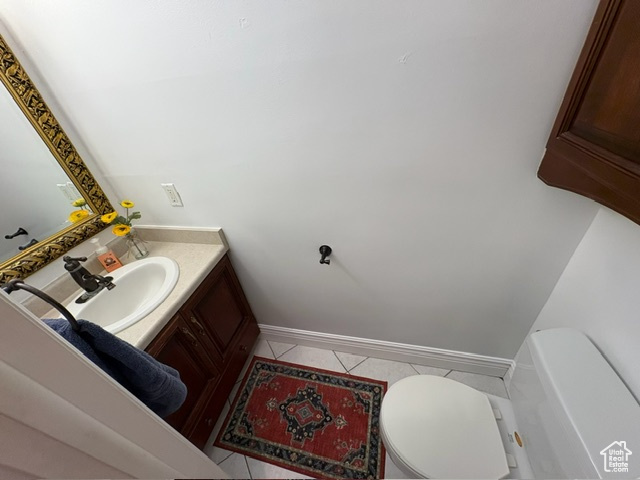 Bathroom featuring toilet, tile patterned floors, vanity, and baseboards