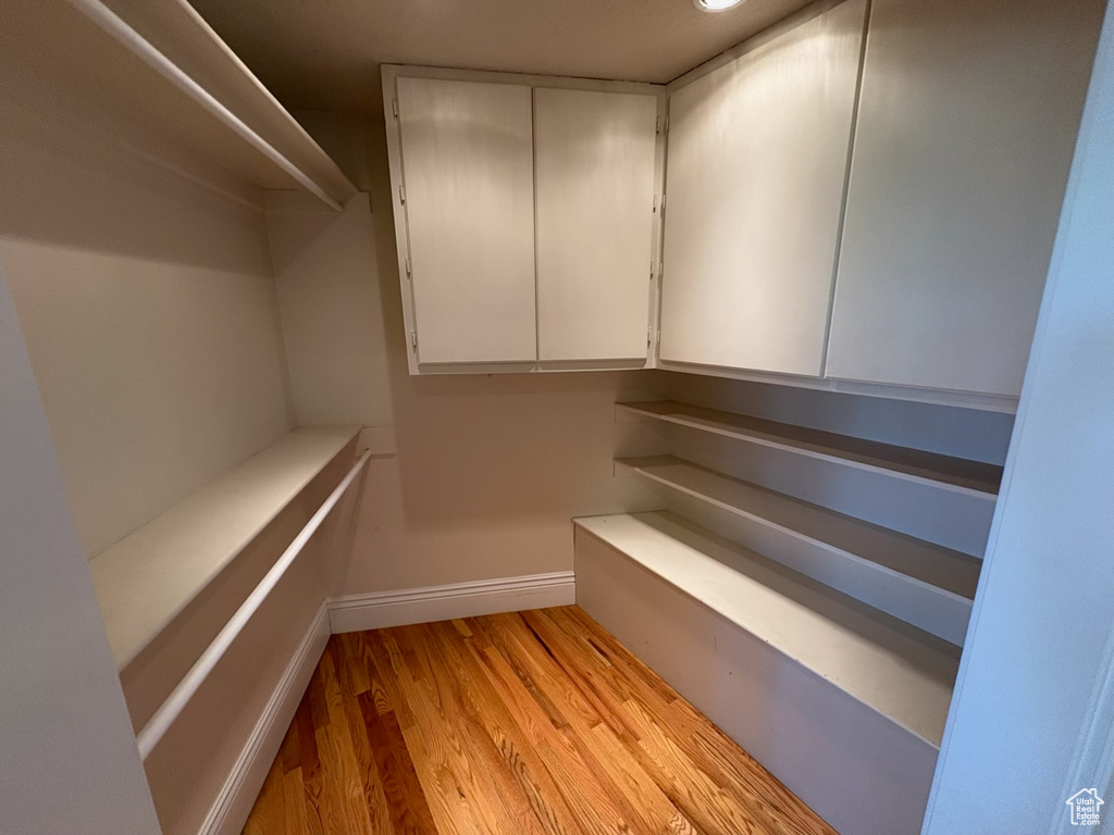 Walk in closet with light wood-style floors