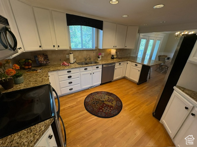 Kitchen featuring dishwasher, electric range, a sink, black microwave, and light wood-style floors
