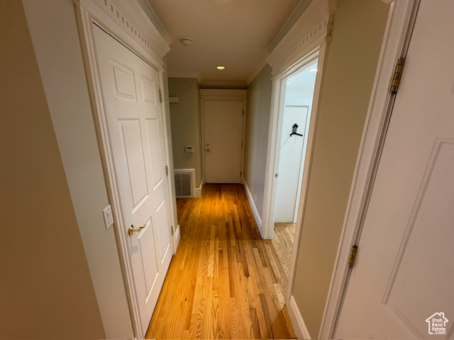 Corridor with ornamental molding, light wood-style flooring, baseboards, and recessed lighting
