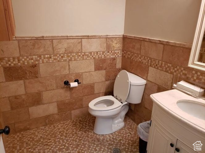Bathroom with vanity, a wainscoted wall, tile walls, and toilet
