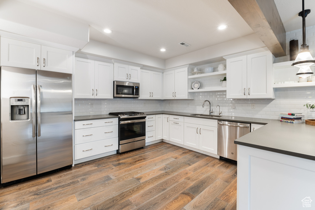 Kitchen featuring dark countertops, appliances with stainless steel finishes, open shelves, and a sink