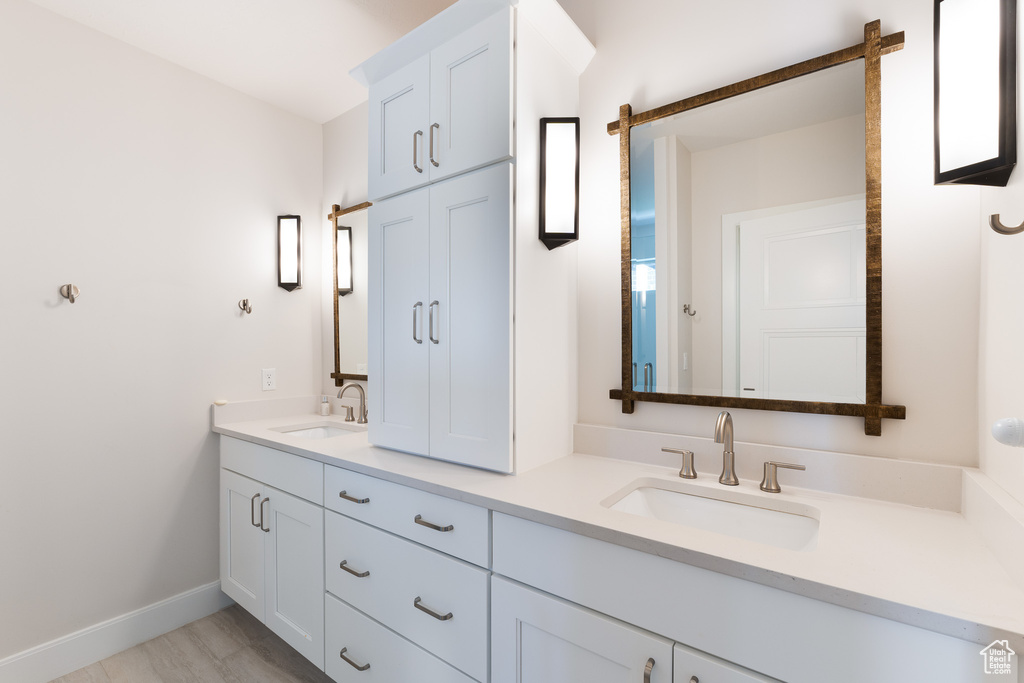 Full bathroom with baseboards, a sink, and double vanity